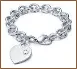 A silver bracelet with a heart charm and initials.