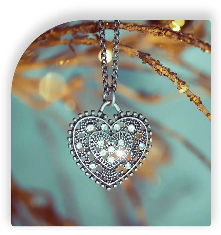 A heart shaped necklace hanging on a tree branch.